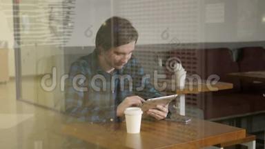在咖啡馆工作的年轻企业家，在带眼镜、手机和笔记本电脑的餐馆里看橱窗的自由职业者